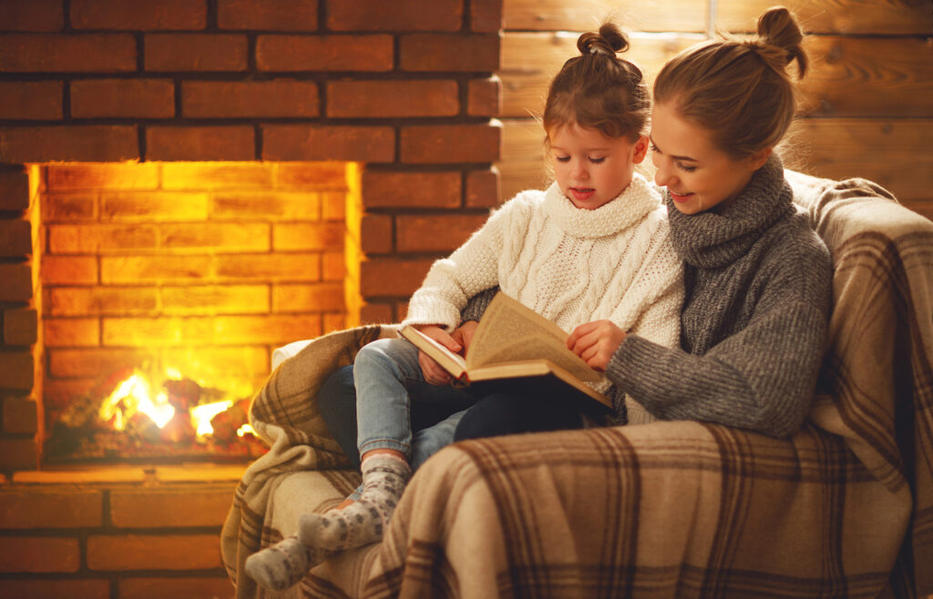 girls reading book near gas fireplace